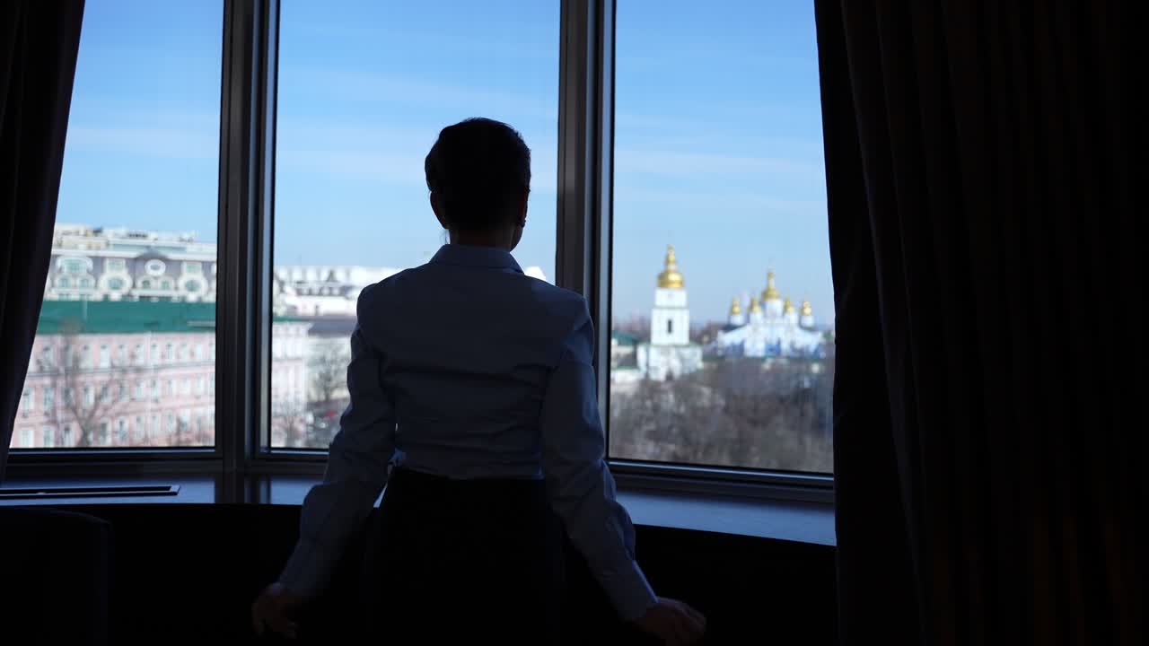Silhouette of woman enjoying view by hotel window