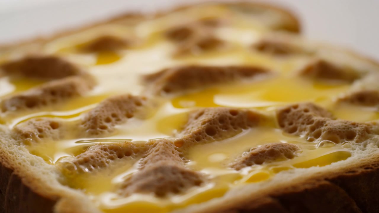 Close-up toasted bread cups holding cracked eggs, glossy yolks settling into soft wells under diffused light for warm breakfast food visuals and rich texture detail