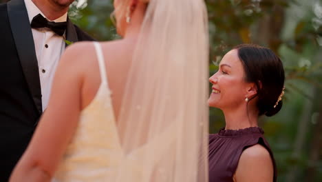 smiling celebrant talking to bride and groom at outdoor garden wedding ceremony, close up 4k slow motion