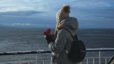 woman takes photos on a winter sea journey from a ferry