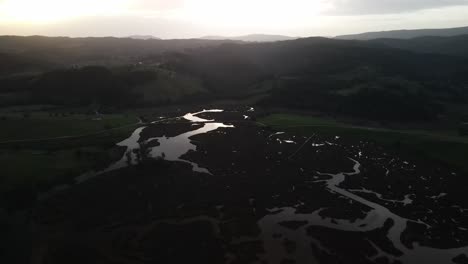 Lake-river-bank-swamp-marsh-and-moor-aerial-at-mountain-nature-sunset