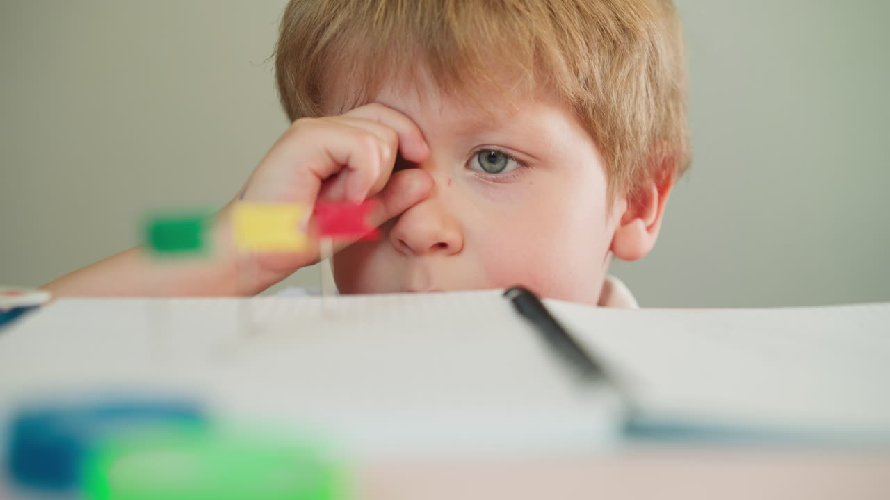 Bambino piccolo guarda attraverso un mirino immaginario delle puntine con bandiere.