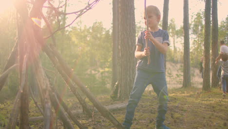 A-boy-collects-and-wears-sticks-for-a-campfire-during-a-hike.-Forest-caster-for-cooking-and-frying-marshmallows