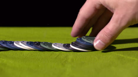 mano extendiendo fichas de casino en la superficie verde