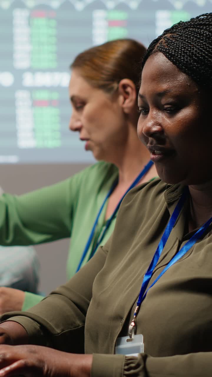Vertikal video: Afroamerikansk analytiker og kolleger gennemgår årlig datarapportering.