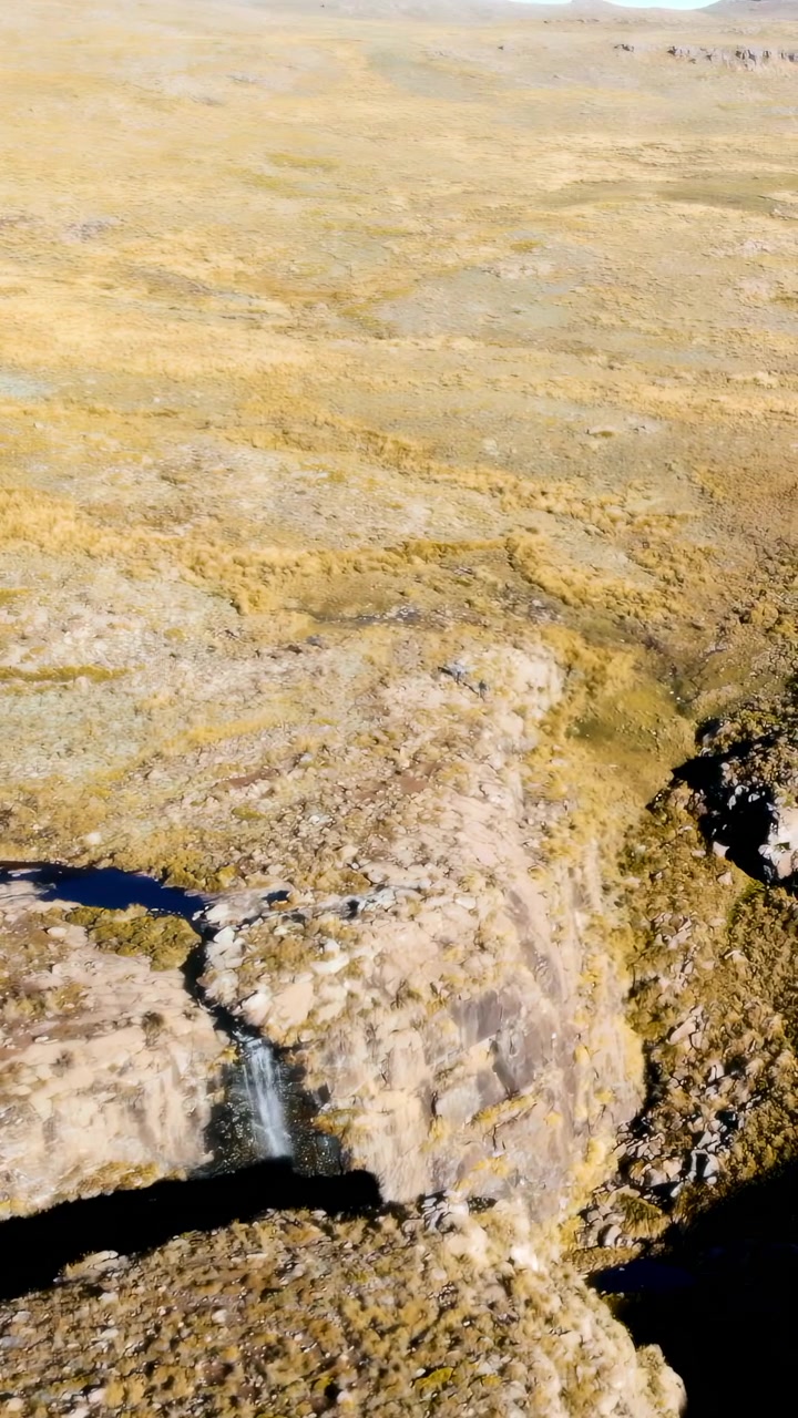 Vista aerea da drone di un canyon in ombra, gola e crepaccio, ripide scogliere che proiettano ombre profonde su un terreno accidentato.
