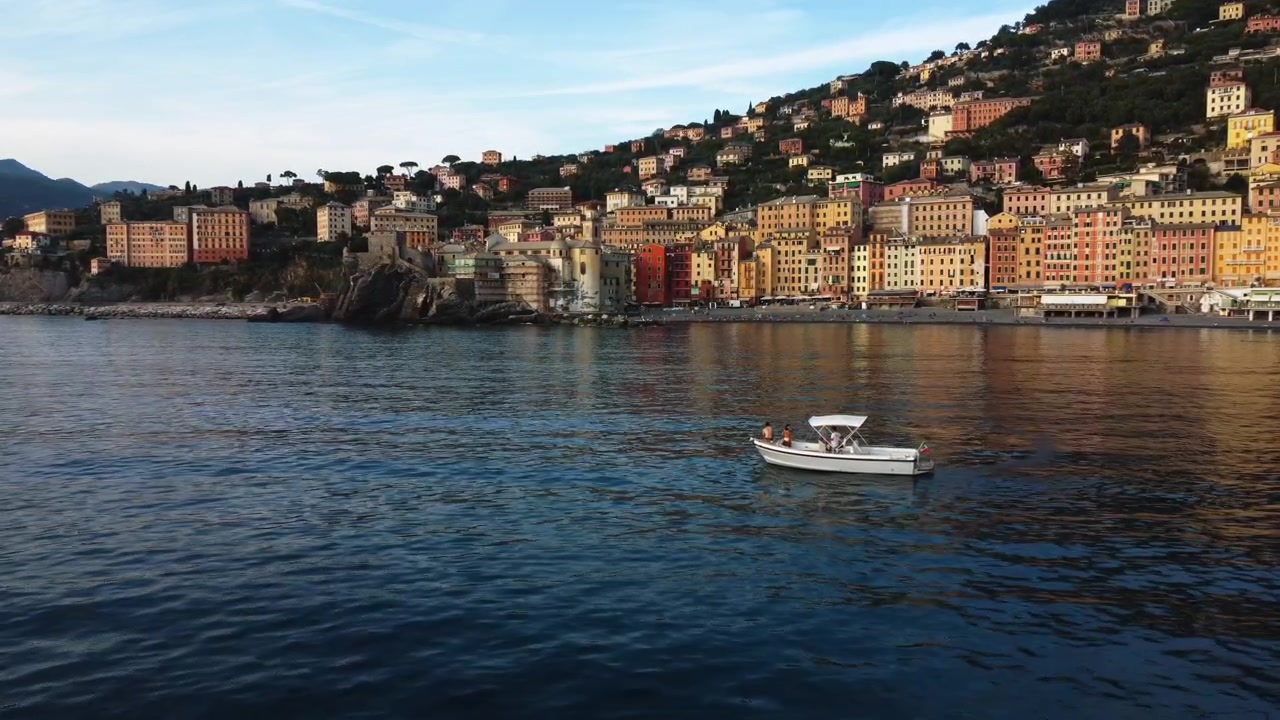 Vista aerea verso una barca davanti allo skyline della città di Camogli, una sera di sole in Italia.