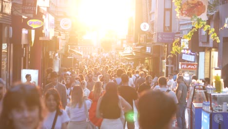 crowded street with people walking towards the sunset