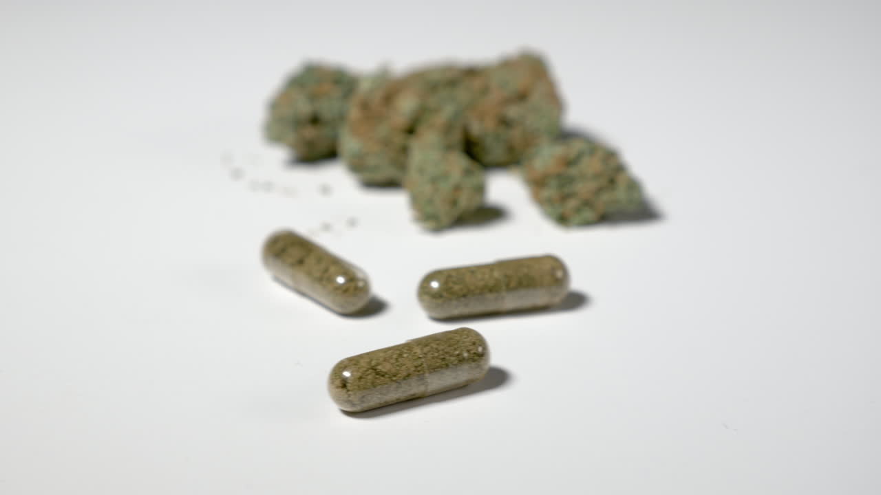 Panning past three capsules of medical cannabis and dried marijuana in background. Room for copy on left.