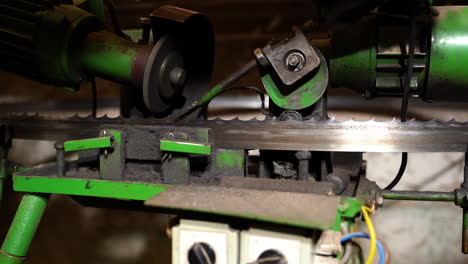 Bandsaw sharpening machine operator adjusting grinding settings for maintenance