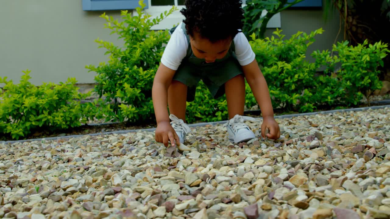 Untersicht eines süßen kleinen schwarzen Babys, das im Garten seines Hauses spielt 4K