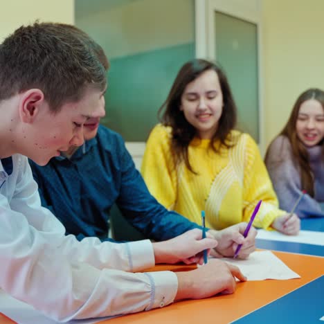 happy children at school. students writing joyfully during studying. female teacher and teenage pupils in the classroom. positive emotions at the lesson.