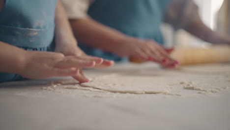 la niña y su madre están cocinando pasteles en casa el fin de semana. la mujer está sacando la masa.