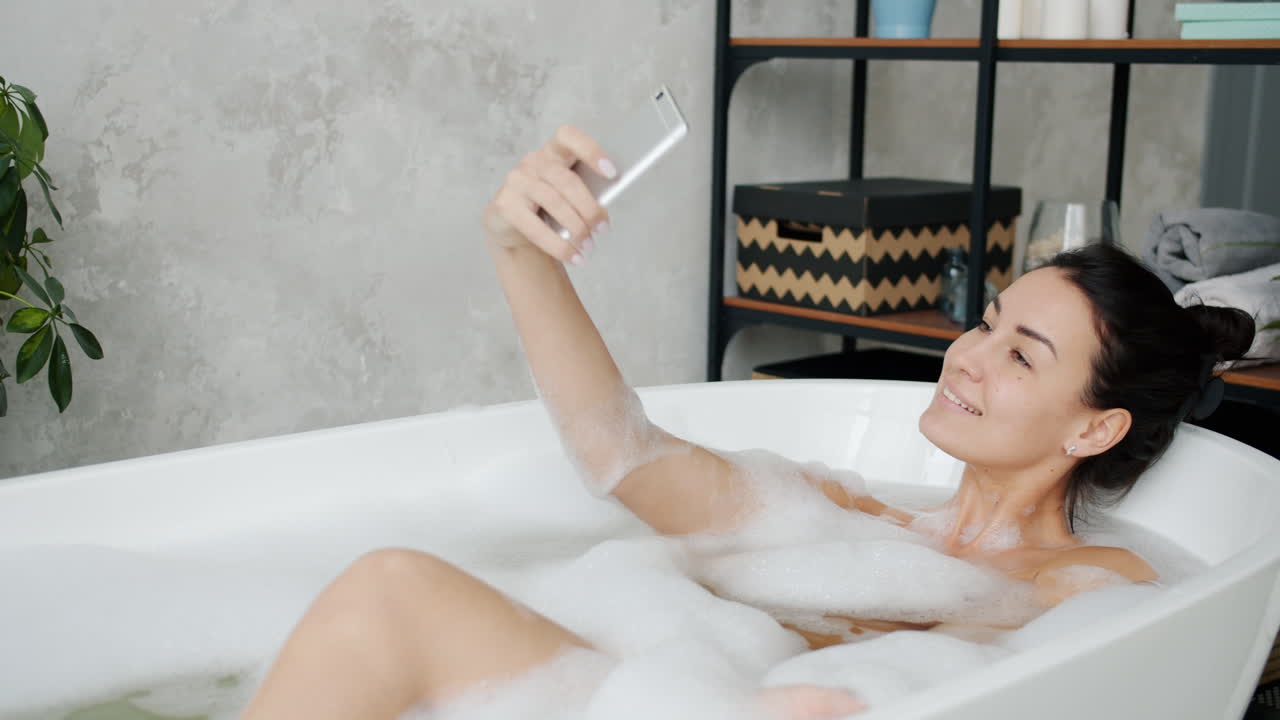 거품 욕조에서 셀피를 찍는 여자