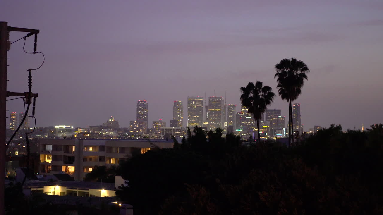 Splendido cielo viola della California al tramonto sopra gli edifici del centro e le palme, mentre gli aerei sorvolano
