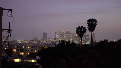 beautiful purple california sky during sunset above downtown buildings and palm trees as planes fly over