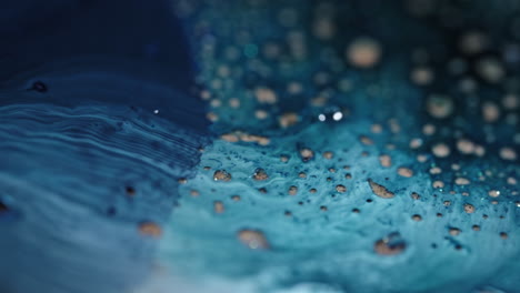 blue and white liquids swirling and mixing together in a close-up macro shot with floating droplets