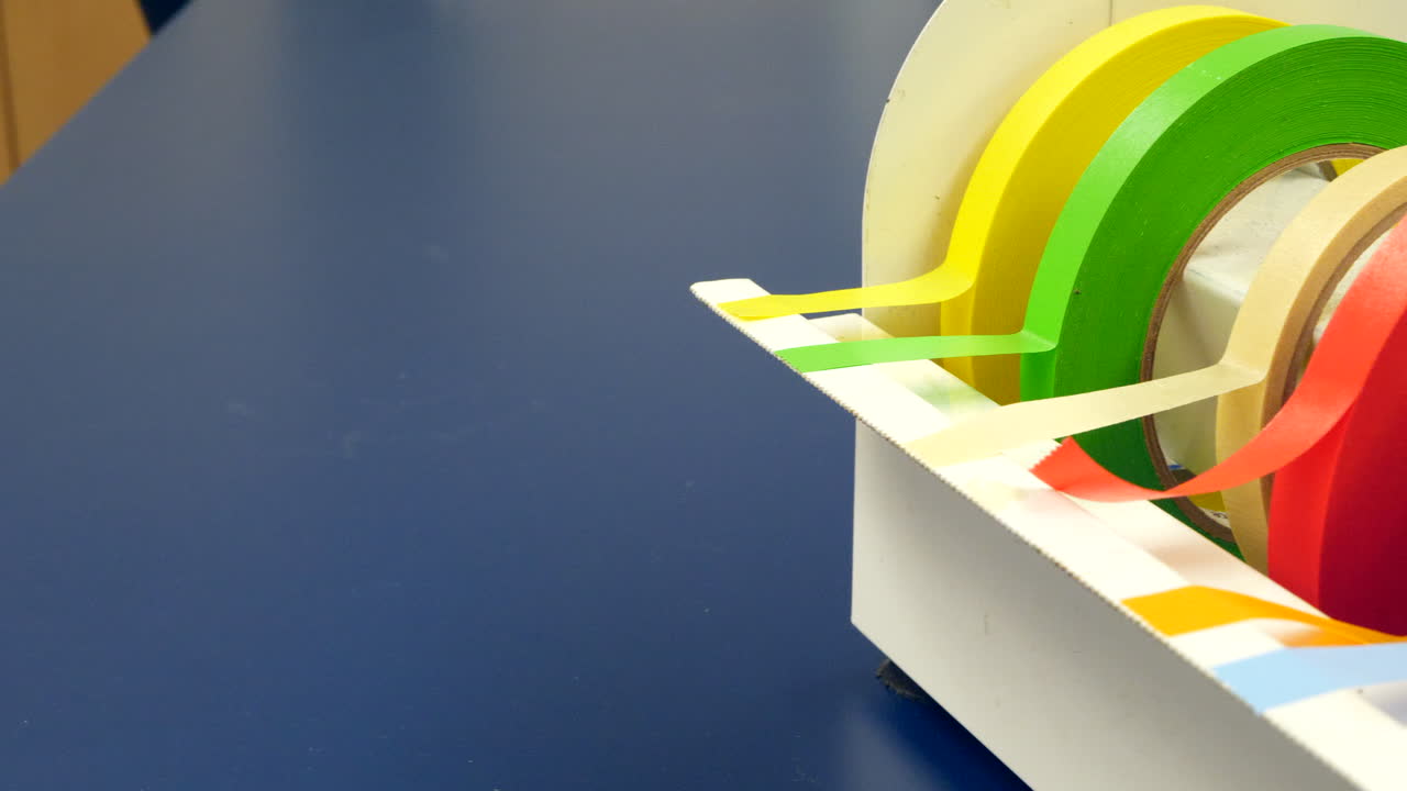 Close up on a scientist grabbing a piece of red tape to mark a piece of equipment during an experiment in a medical research laboratory