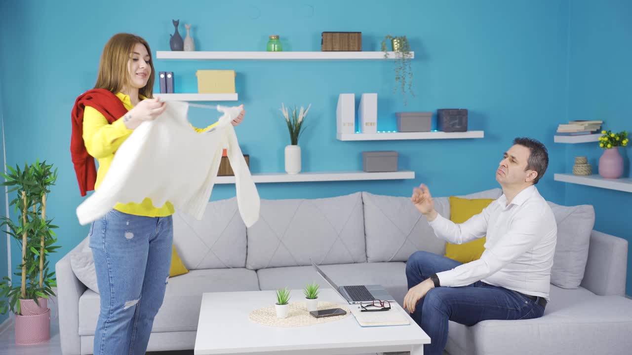 la niña consulta con su padre, que trabaja en la computadora portátil, sobre la ropa que debe usar.