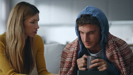 ill husband wiping nose talking wife at living room closeup. sickness concept