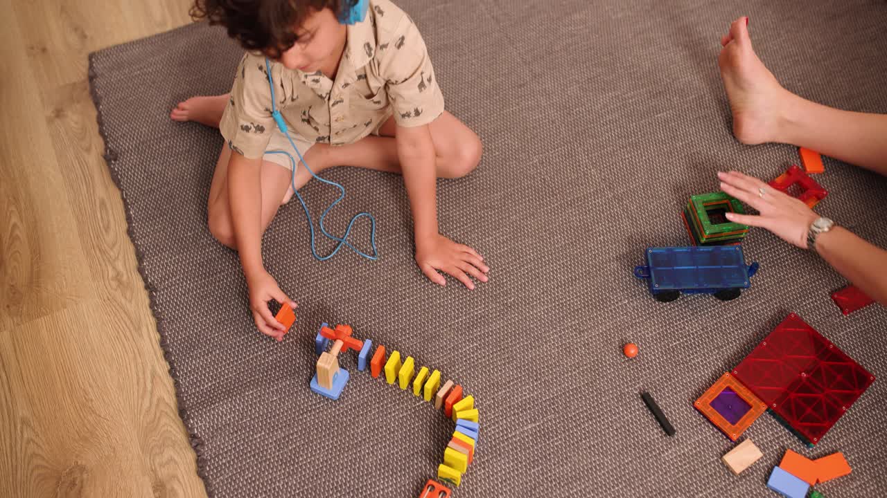 Child playing with colorful wooden toys and listening music with headphones
