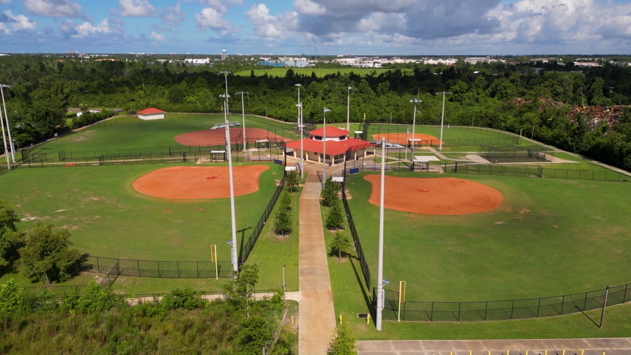 Ripresa con drone in discesa lenta di un piccolo parco da baseball con quattro campi e un edificio per le concessioni.