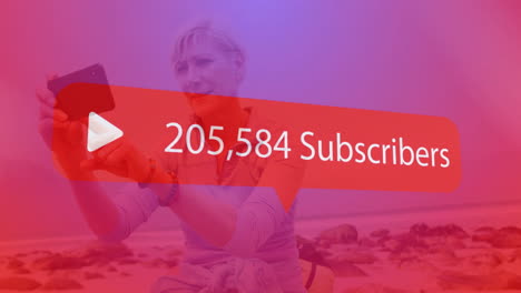 play button and subscriber count animation over person taking selfie on beach