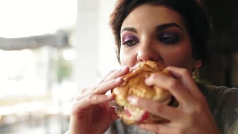 Nahaufnahme-Einer-Jungen-Frau,-Die-Im-Café-Einen-Großen,-Leckeren-Burger-Beißt.-Zeitlupenaufnahme