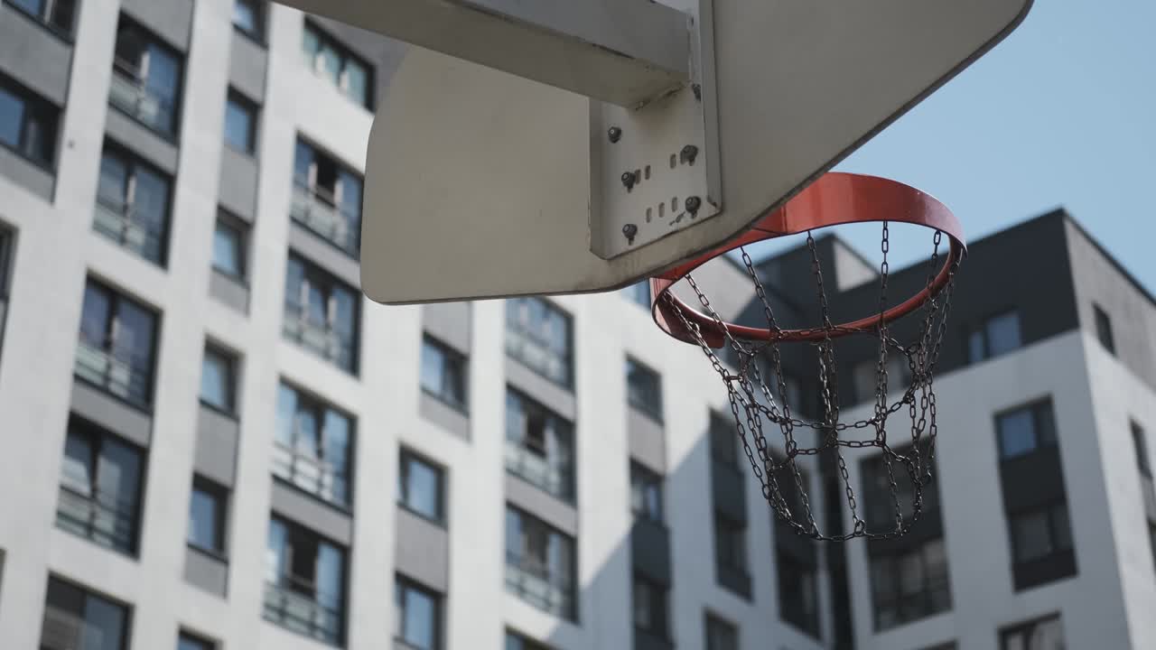 el baloncesto naranja golpea la canasta, la cancha de baloncesto en la calle, día soleado