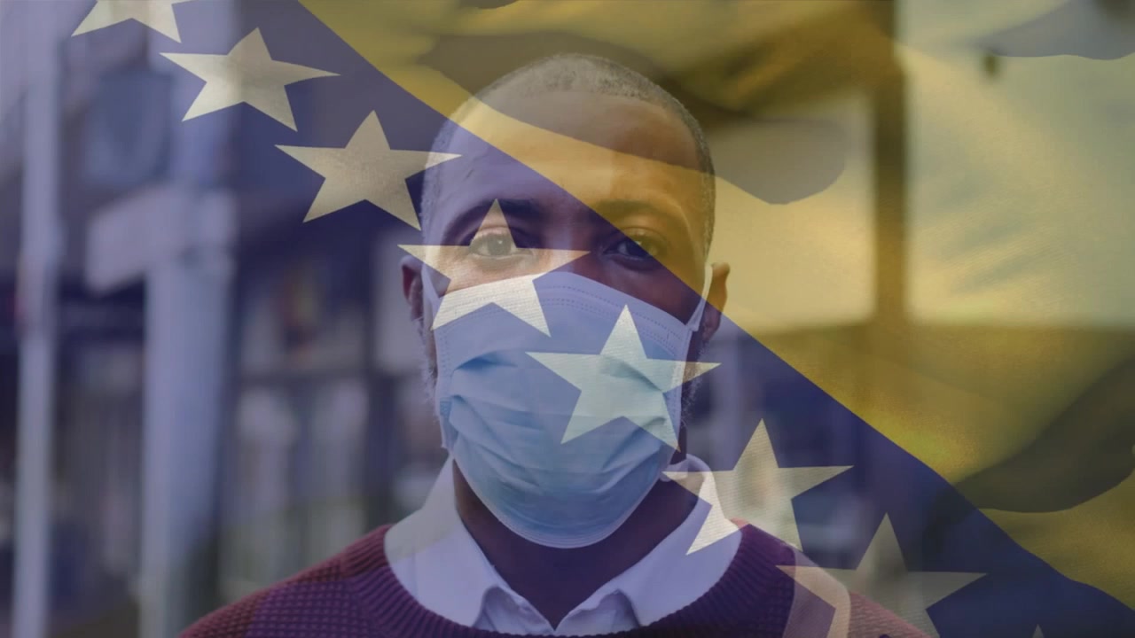 Animazione della bandiera sventolante della Bosnia ed Erzegovina sopra un uomo afroamericano con mascherina per strada