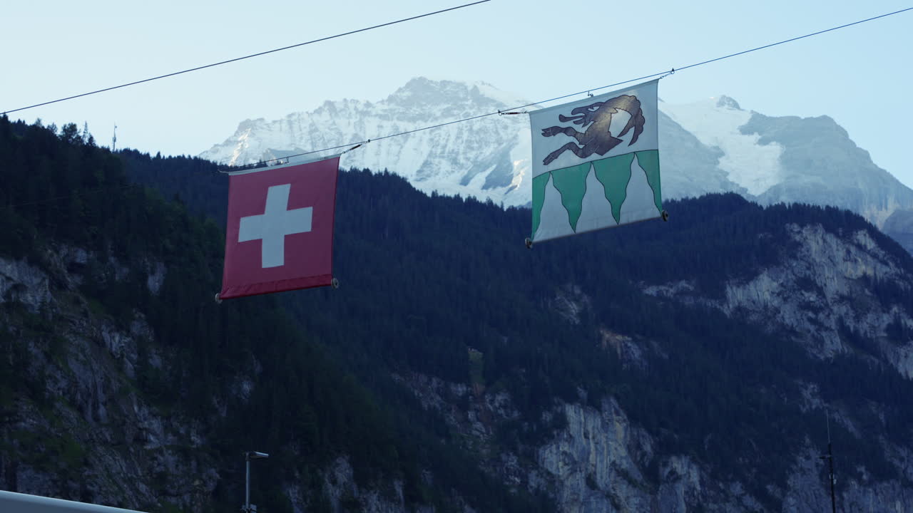 Lauterbrunnen and Switzerland flags against snowy glacial mountain peaks scenery