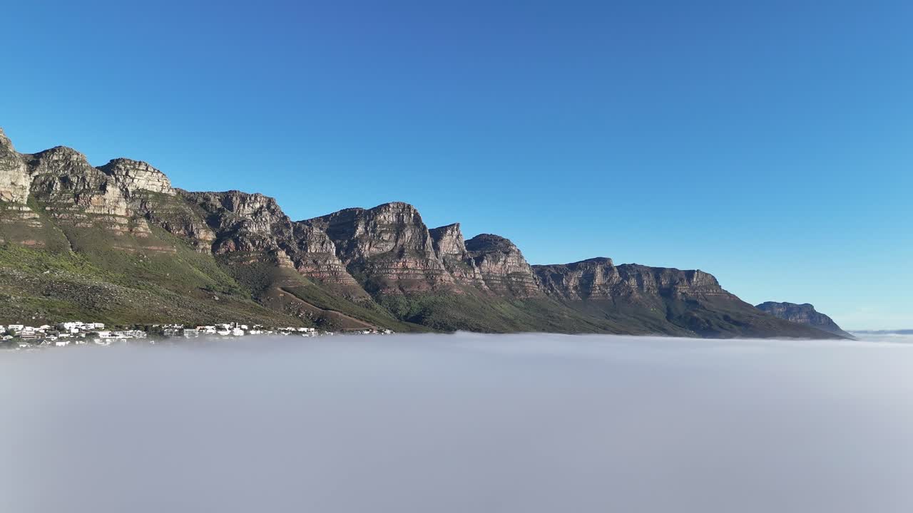 Aerial footage of table mountain in Cape Town, South Africa, surrounded by mist and clouds with only the peak emerging above the fog