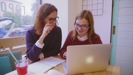 dos mujeres estudiando en un café