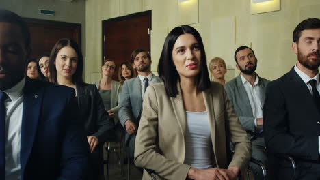 close-up view of the audience at a business conference listening to the speaker, then caucasian businesswoman rises her hand and asks a question