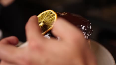 chef decorating a chocolate cake with dried orange slices