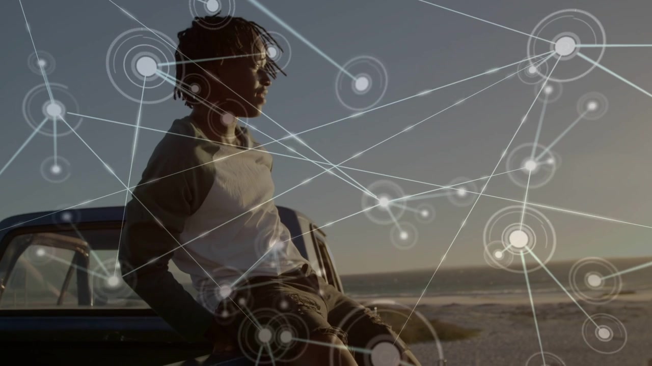 Man placing hands on hood lifting knee climbing onto truck watching ocean with tech nodes spreading