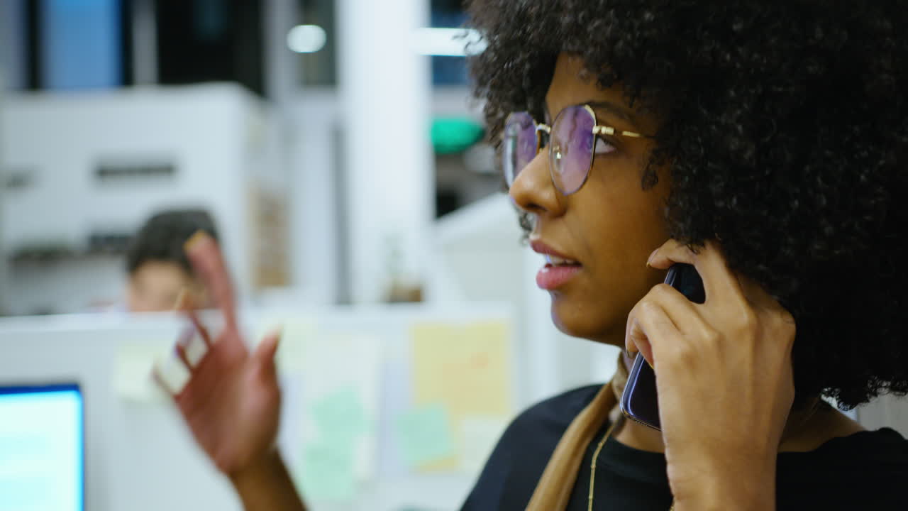 African-American Woman Discussing Business on Phone at Office Cubicle