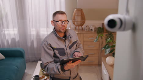 professional technician installing or servicing a smart home security camera system with a tablet