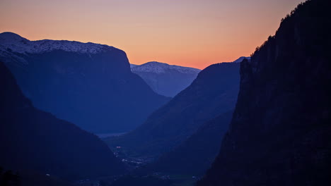 time lapse panorama wide shot of golden sunset behind snowy mountain range in norway