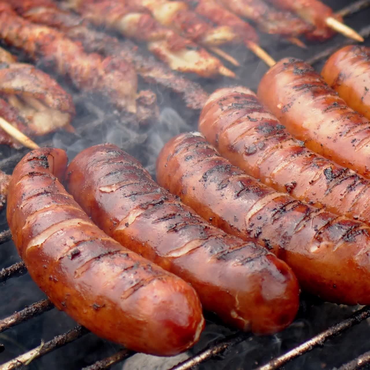 salchichas asadas calientes y sabrosas que se fríen en un video de cámara lenta de barbacoa humeante