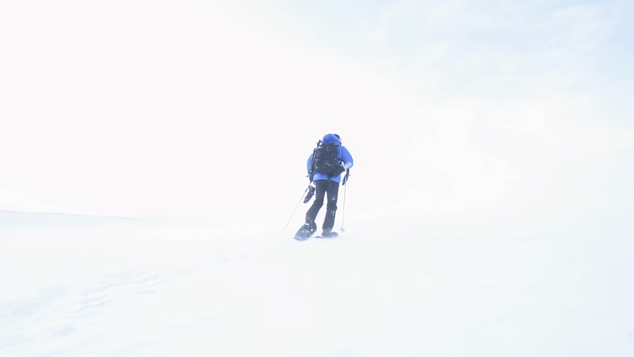 un turista en raquetas de nieve sube la colina, tema de invierno