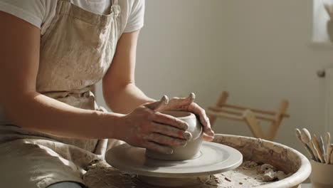 person shaping clay on a potter's wheel