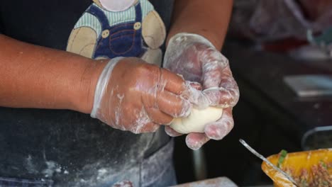 Handmade-authentic-Xian-Bing-meat-pie,-a-stall-vendor-filling-a-dough-pastry-with-minced-pork-and-spring-onions-before-sealing-it-to-perfection,-close-up-shot-of-Taiwanese-popular-street-food