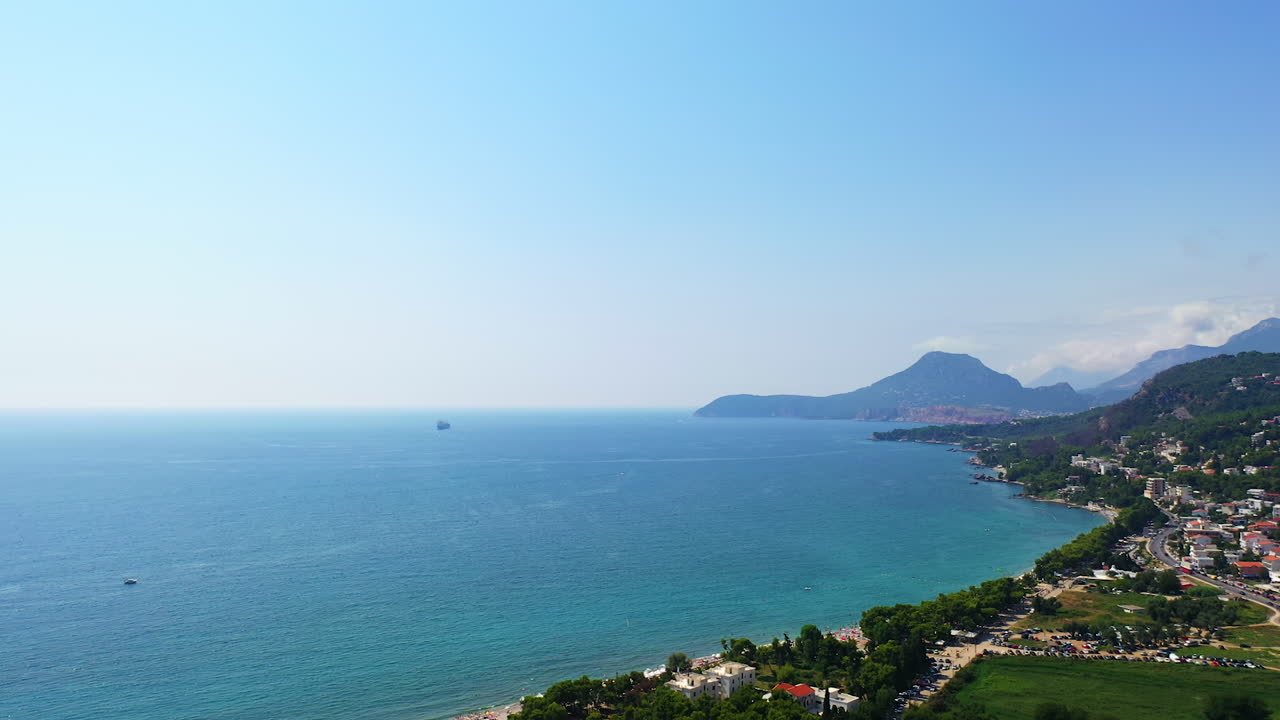 Coast of the Adriatic Sea in the city of Bar, Montenegro. Picturesque view of the urban terrain on the slopes of gorgeous green mountains. Aerial view.