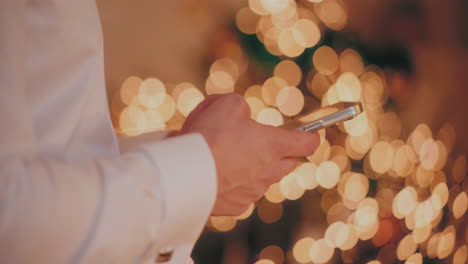 man using cellphone at illuminated home during christmas