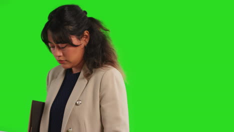 Close-Up-Studio-Shot-Of-Female-Teacher-Or-Businesswoman-Reading-Notebook-Against-Green-Screen-Background