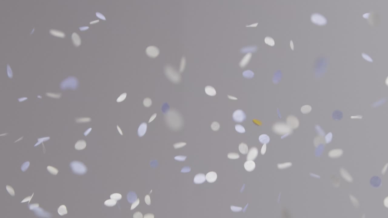 회색 배경에 떨어지는 흰색 파란색과 금색 색종이의 고정 샷