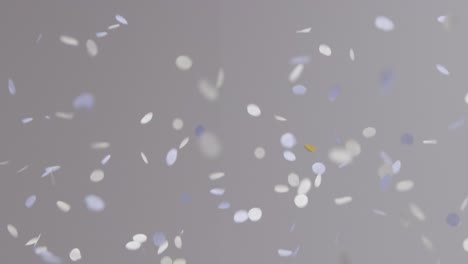 Stationary-Shot-of-White-Blue-and-Gold-Confetti-Falling-Against-Grey-Background