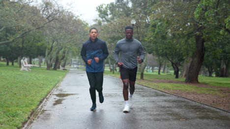 two men jogging in a park on a rainy day