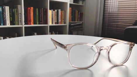 modern eyeglasses in light colour lie on a white table, bright glasses frame, slow motion footage